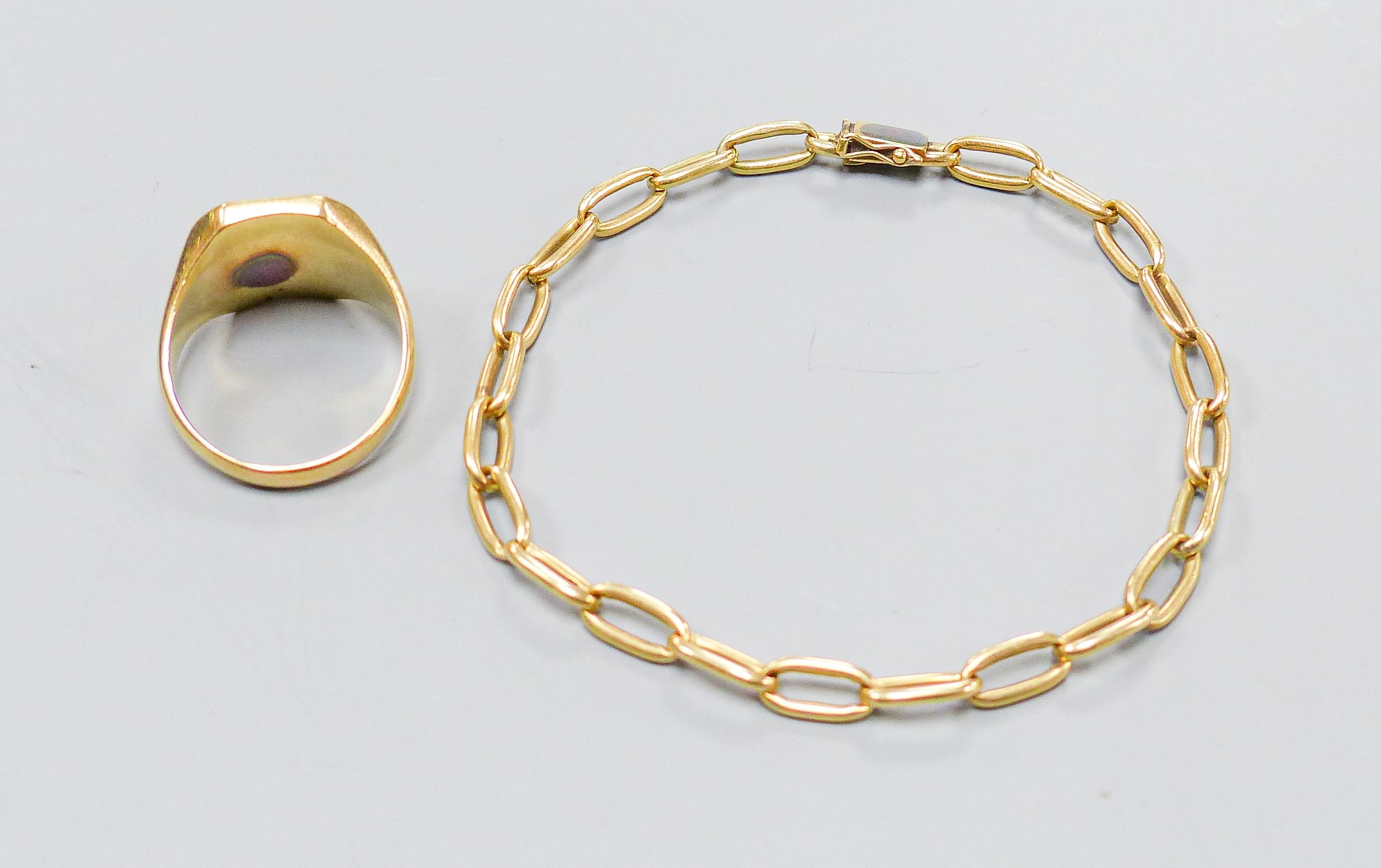 A yellow metal signet ring, inset octagonal intaglio chalcedony matrix, size U, gross 8.3 grams and a yellow metal oval-link bracelet, with box clasp, 10.5 grams.